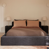 Cosmos Bed in a warm bedroom scene with Gubi bedside lamps and textured bedding, Charcoal fabric.